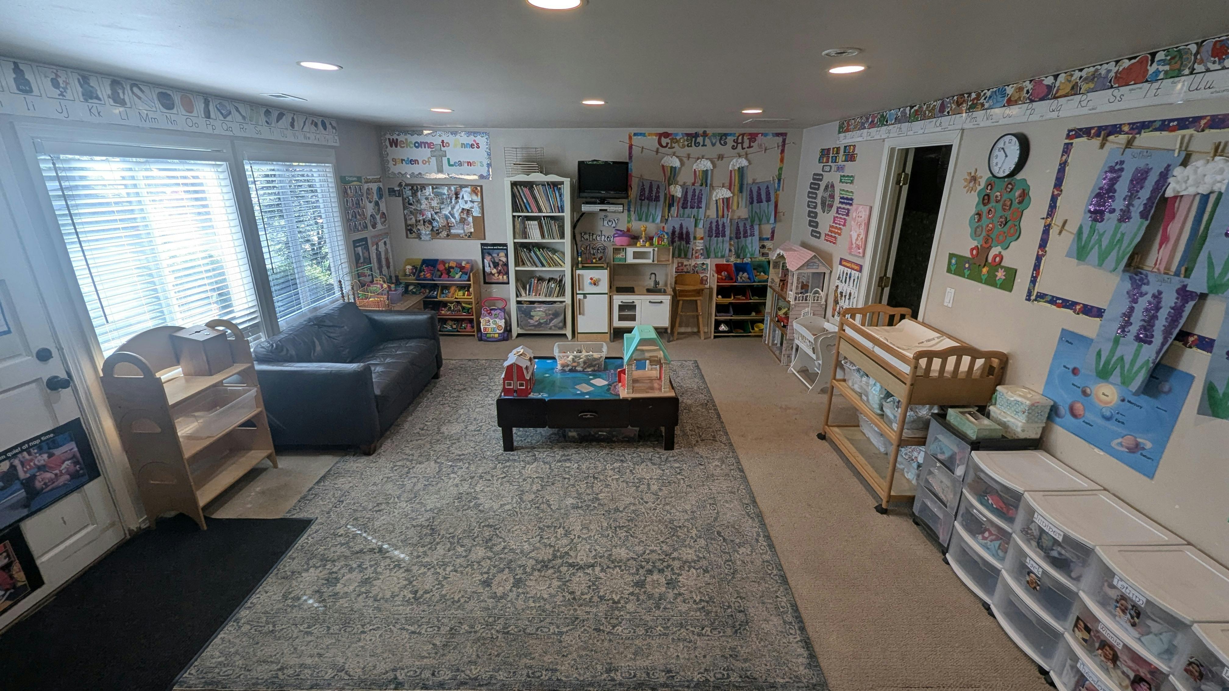 Playroom with a sofa, toy kitchen, changing table, and various educational decorations