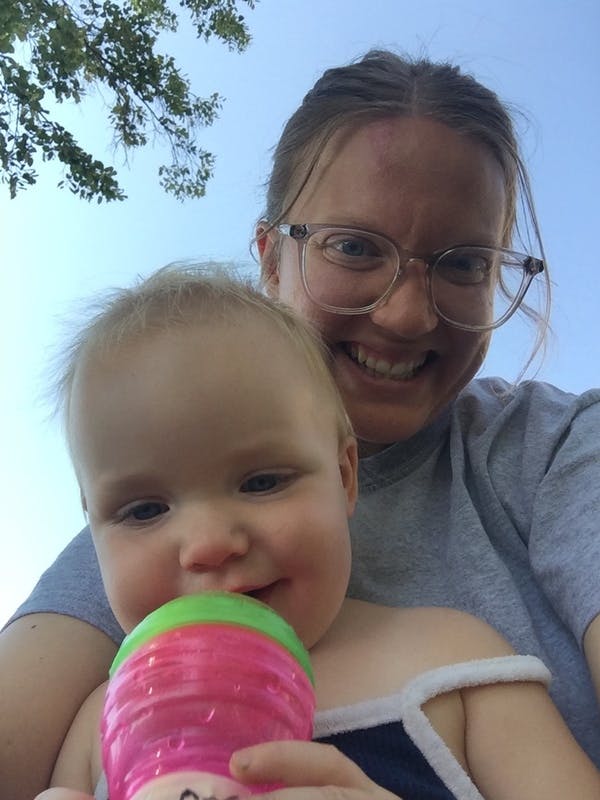 Adult and child looking up at the camera, child holding a colorful cup