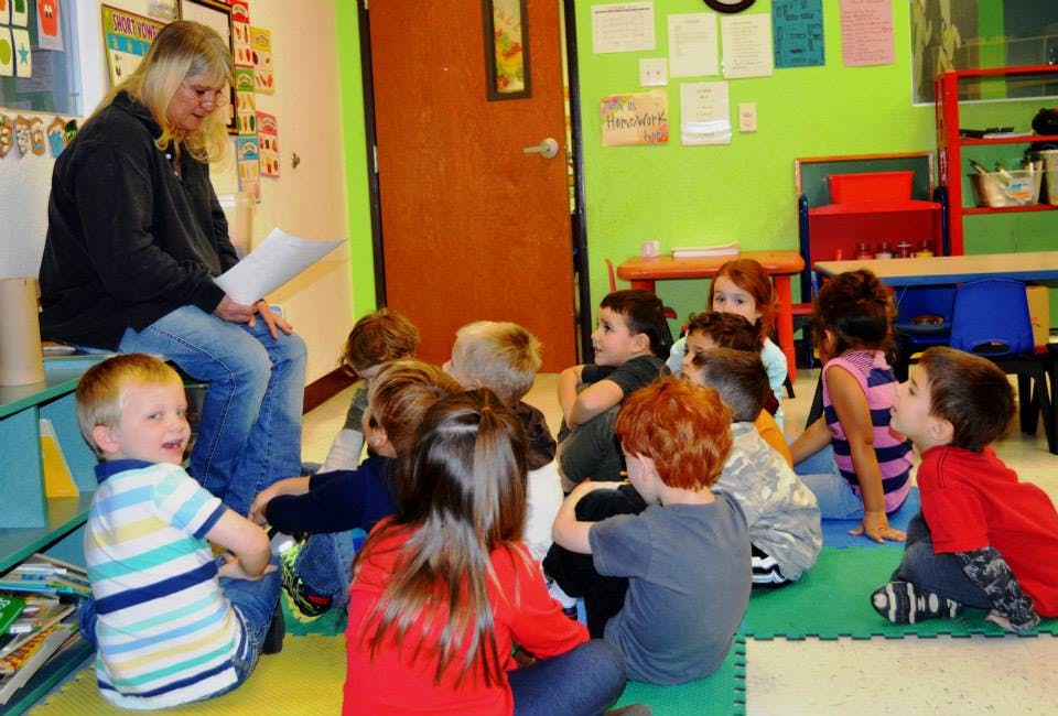 Person reading to a group of children in a classroom