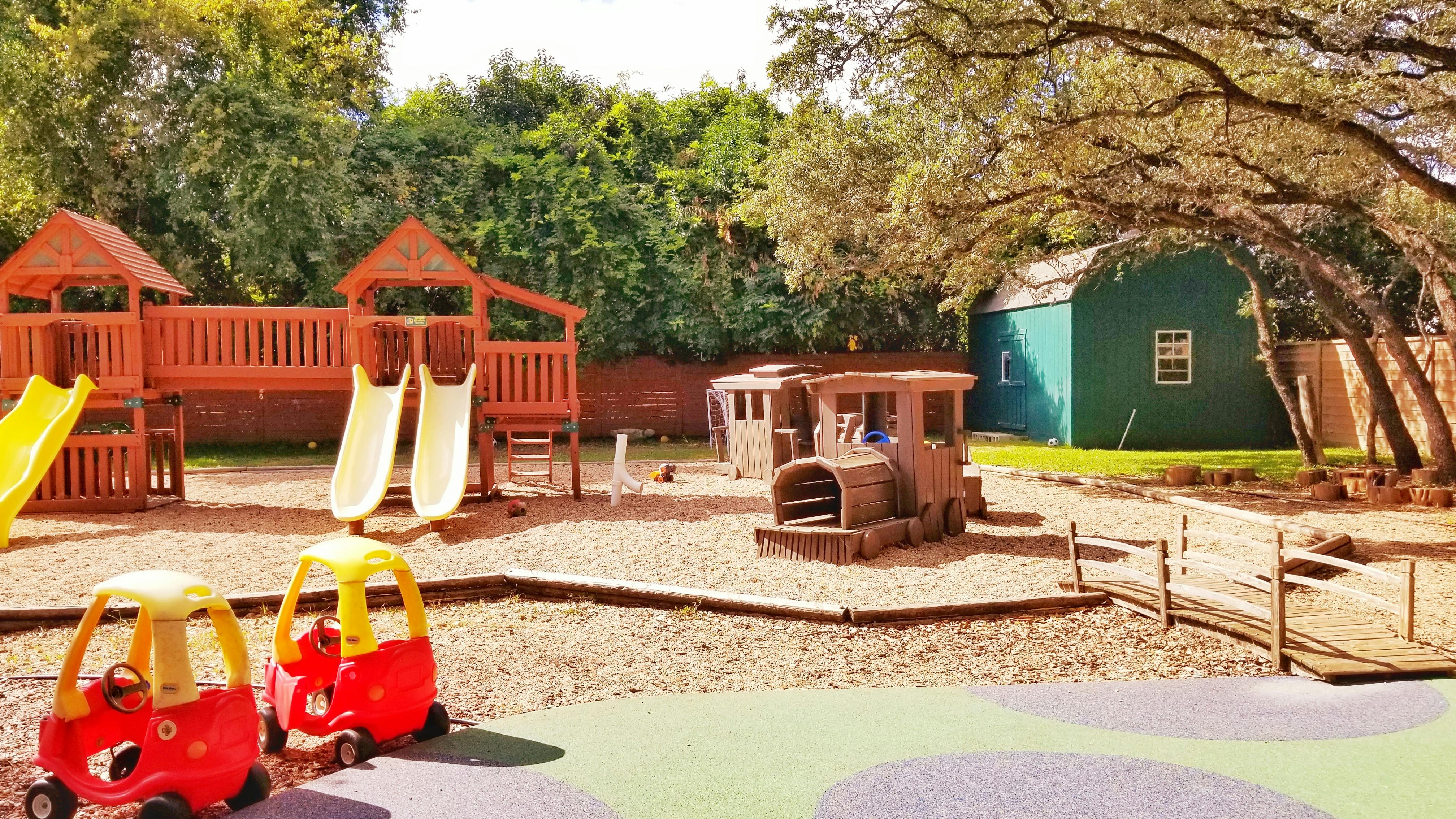 Outdoor playground with slides, play structure, and toy cars