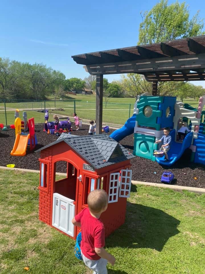 Children playing on a playground with slides and a playhouse