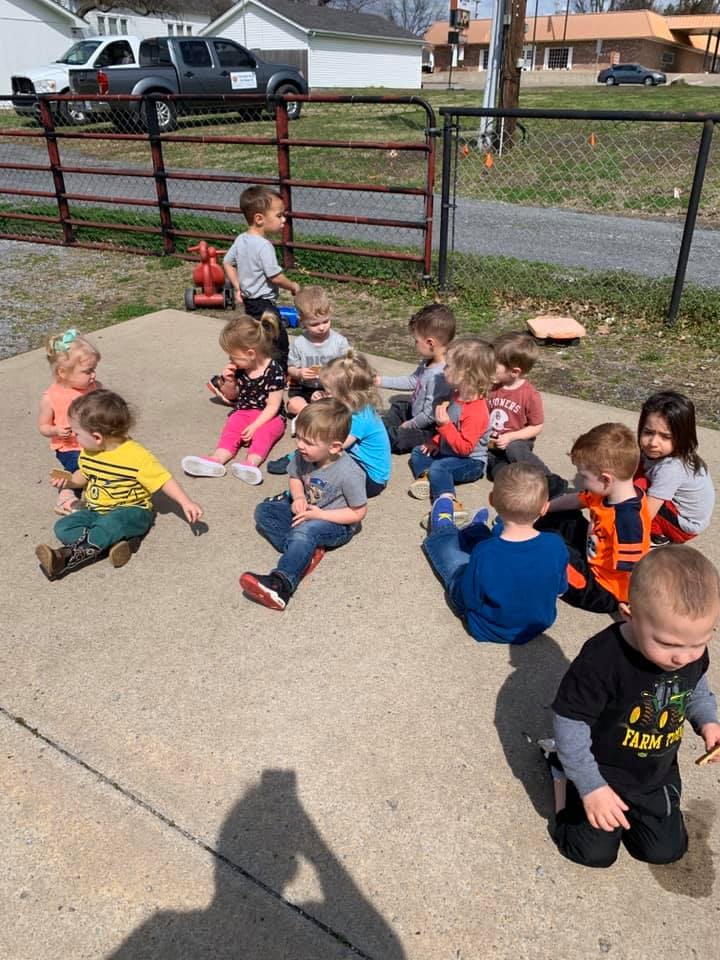 Group of children sitting on the ground outdoors