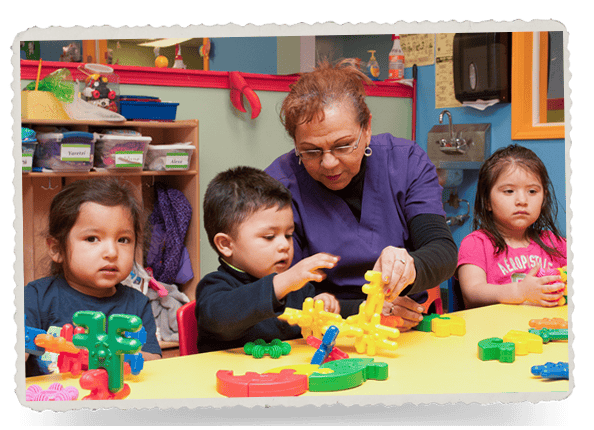 Adult and three children playing with colorful building blocks at a table