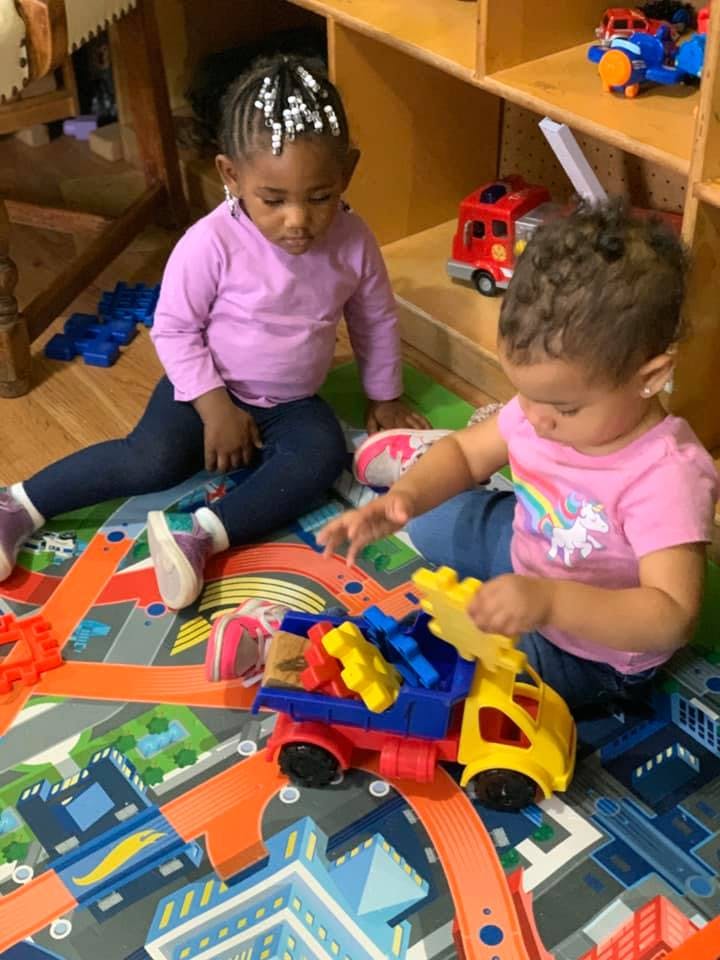 Two children playing with toy trucks on a mat