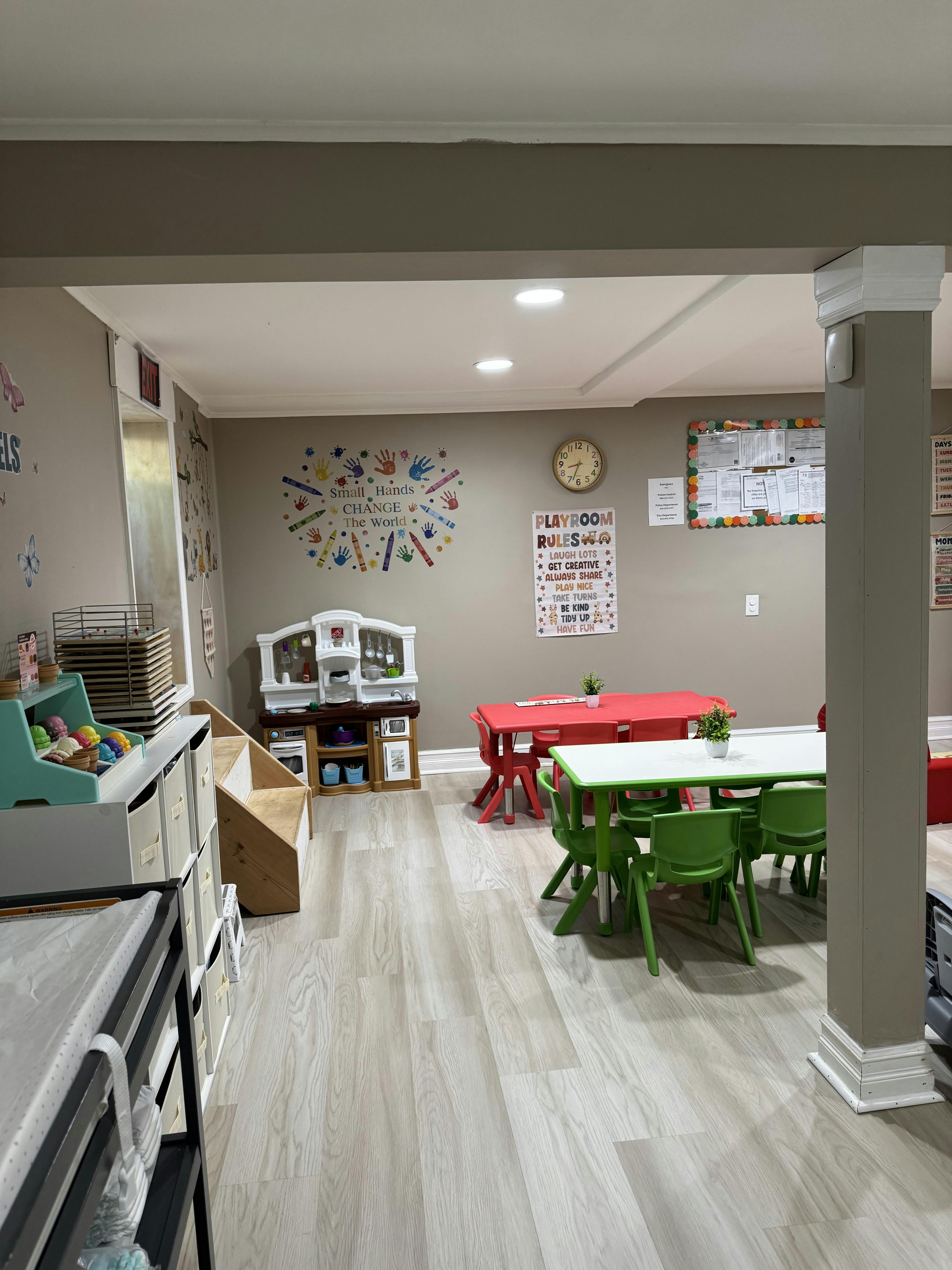 Childcare room with small tables and chairs and a play kitchen