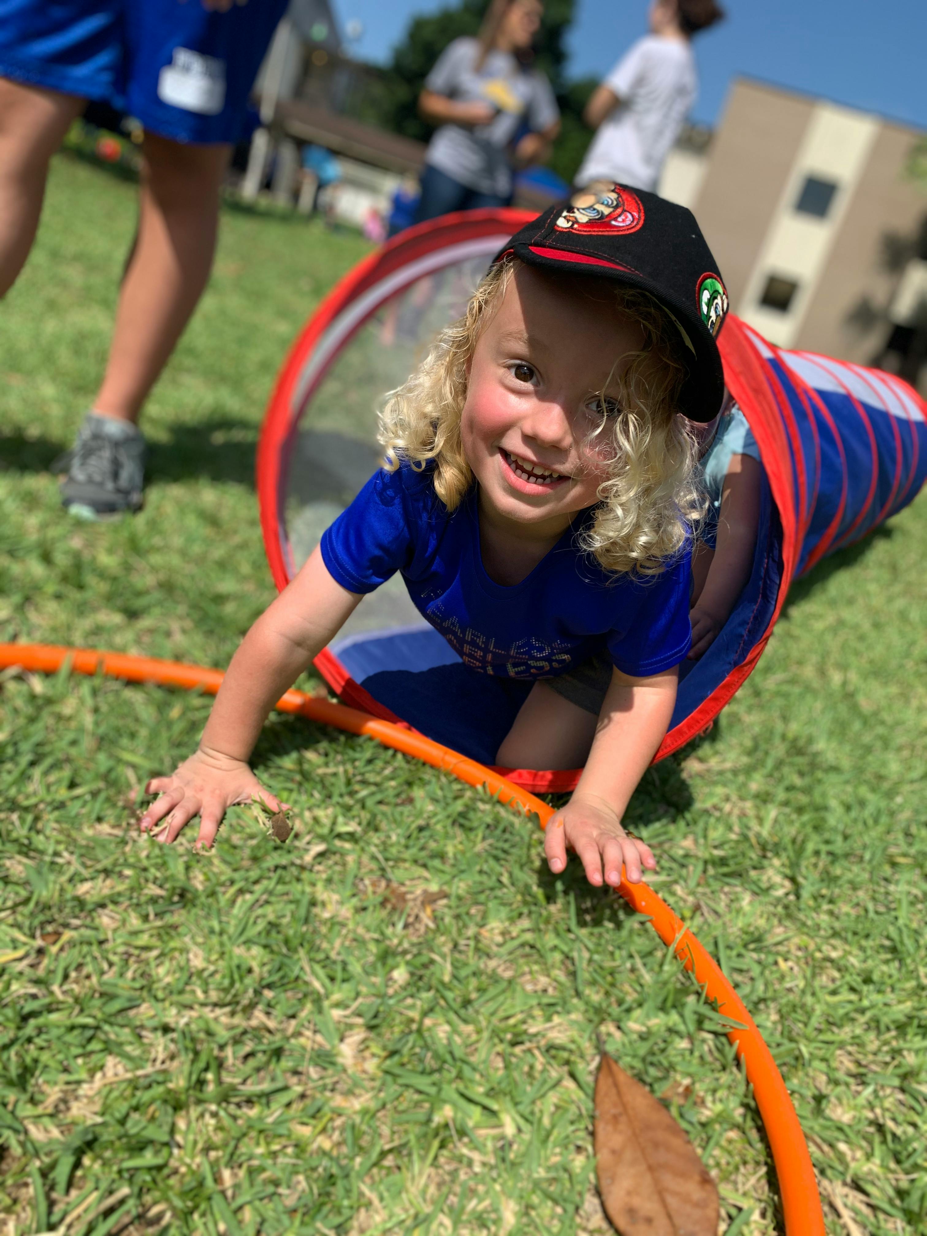Child crawling out of a play tunnel on grass