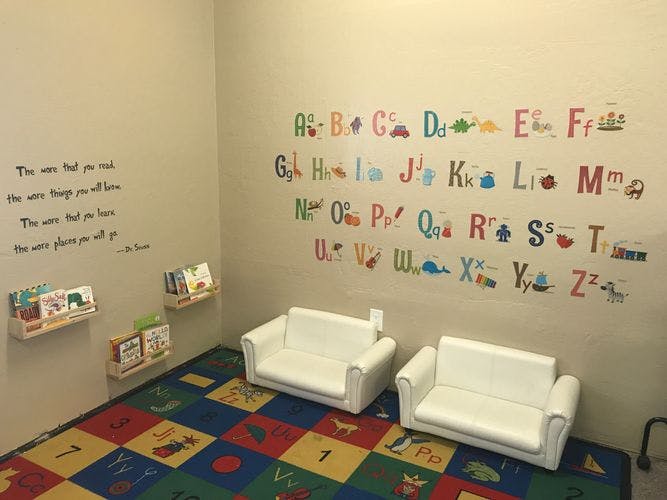 Children's reading nook with alphabet wall decals and small white couches