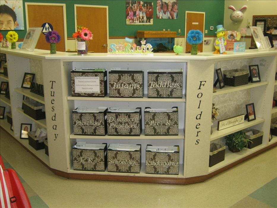 white shelving unit with labeled folders for different age groups