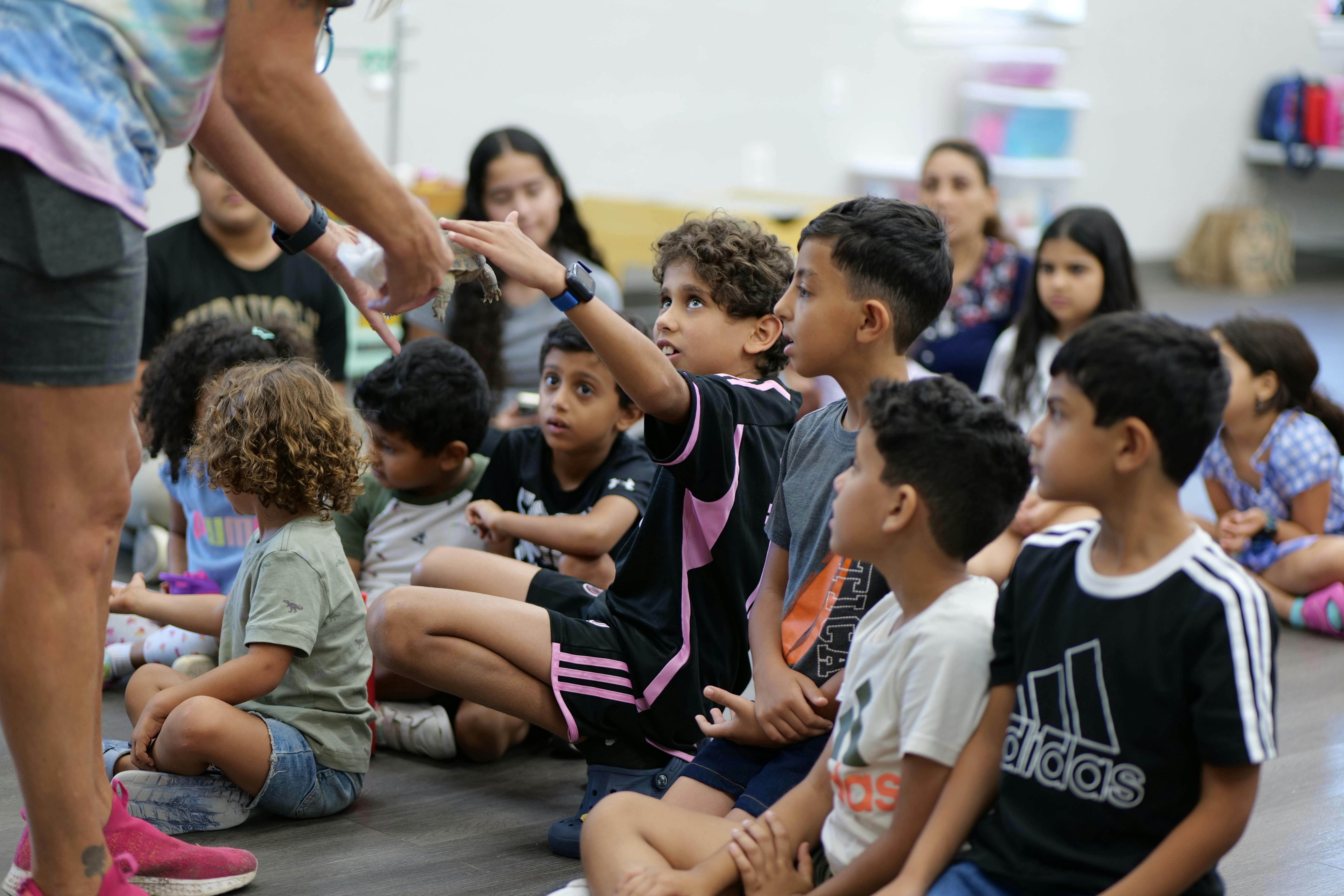 Adult interacting with a group of children sitting on the floor