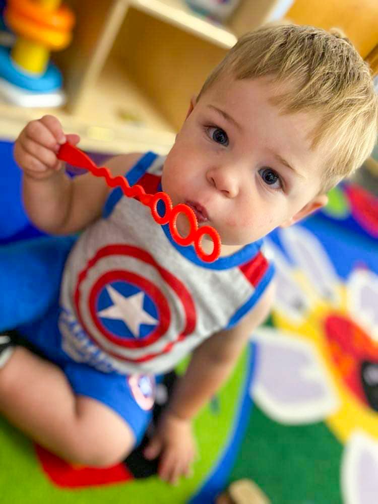 Child in Captain America shirt holding a bubble wand to their mouth