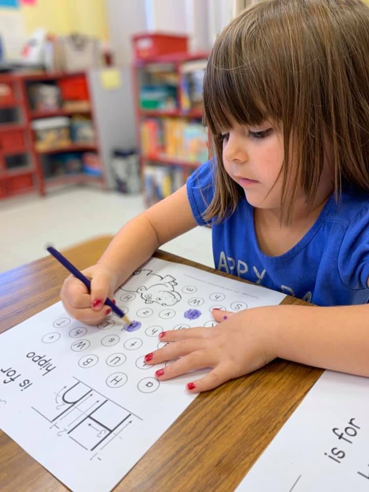 Child coloring a worksheet with a pencil