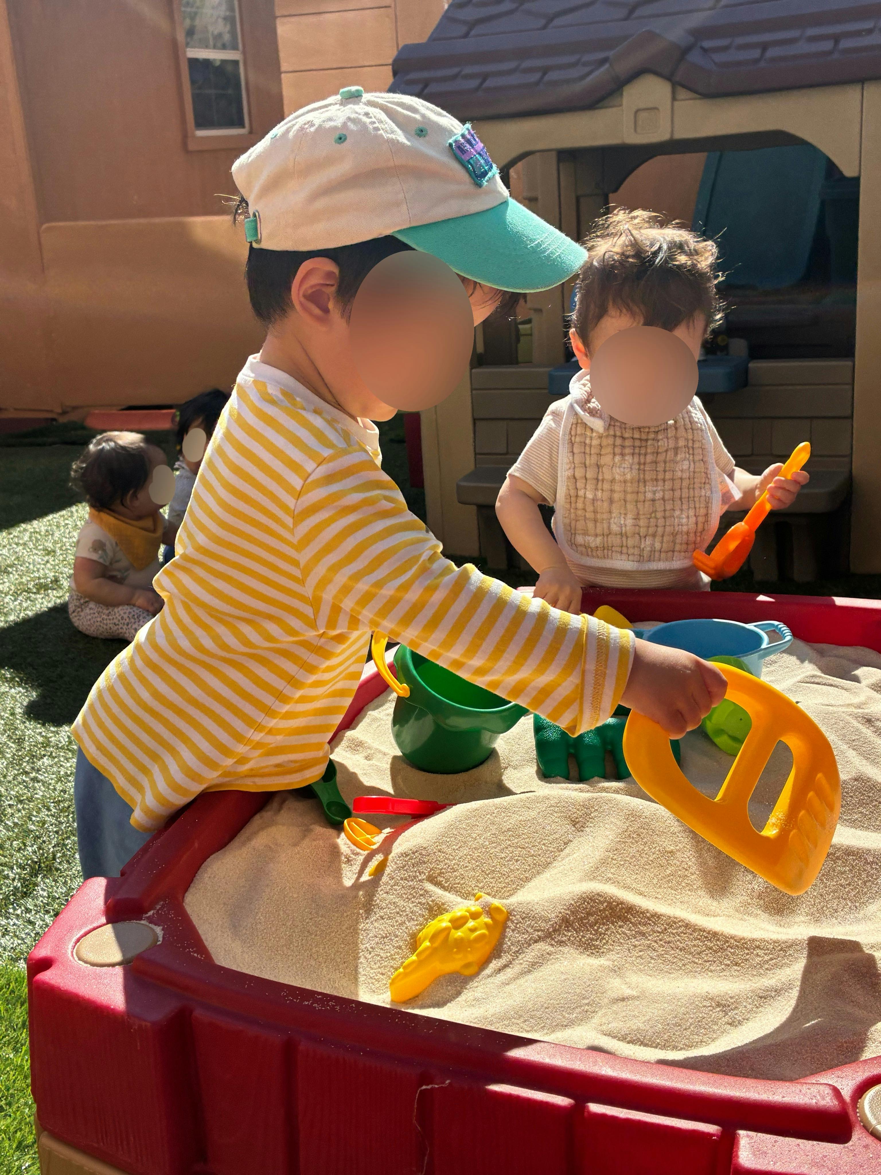 Children playing in a sandbox with toys