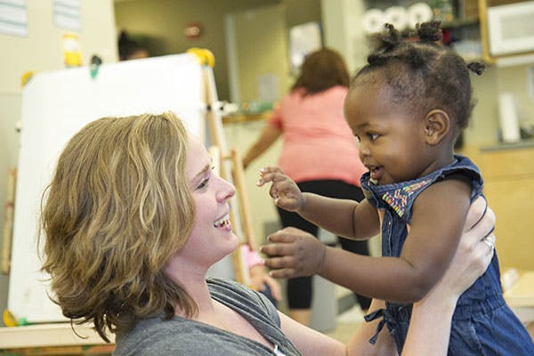 Person holding a child in a classroom