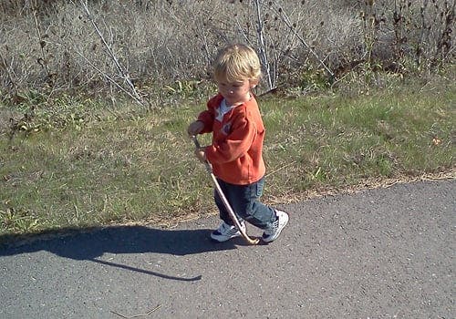 Child walking and holding a stick