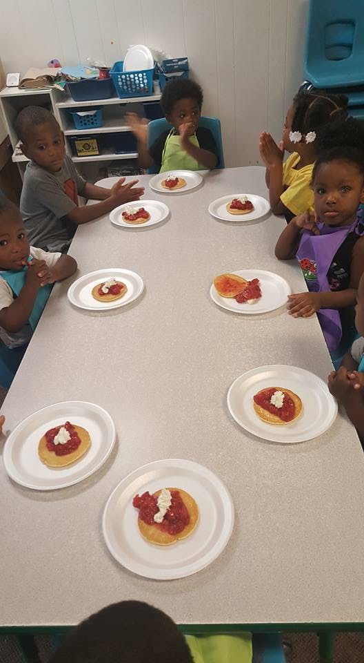 Children sitting at a table with plates of pancakes