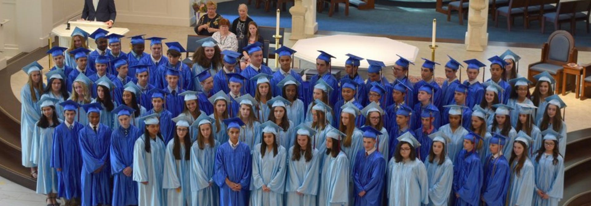 Large group of people in blue and light blue graduation gowns and caps