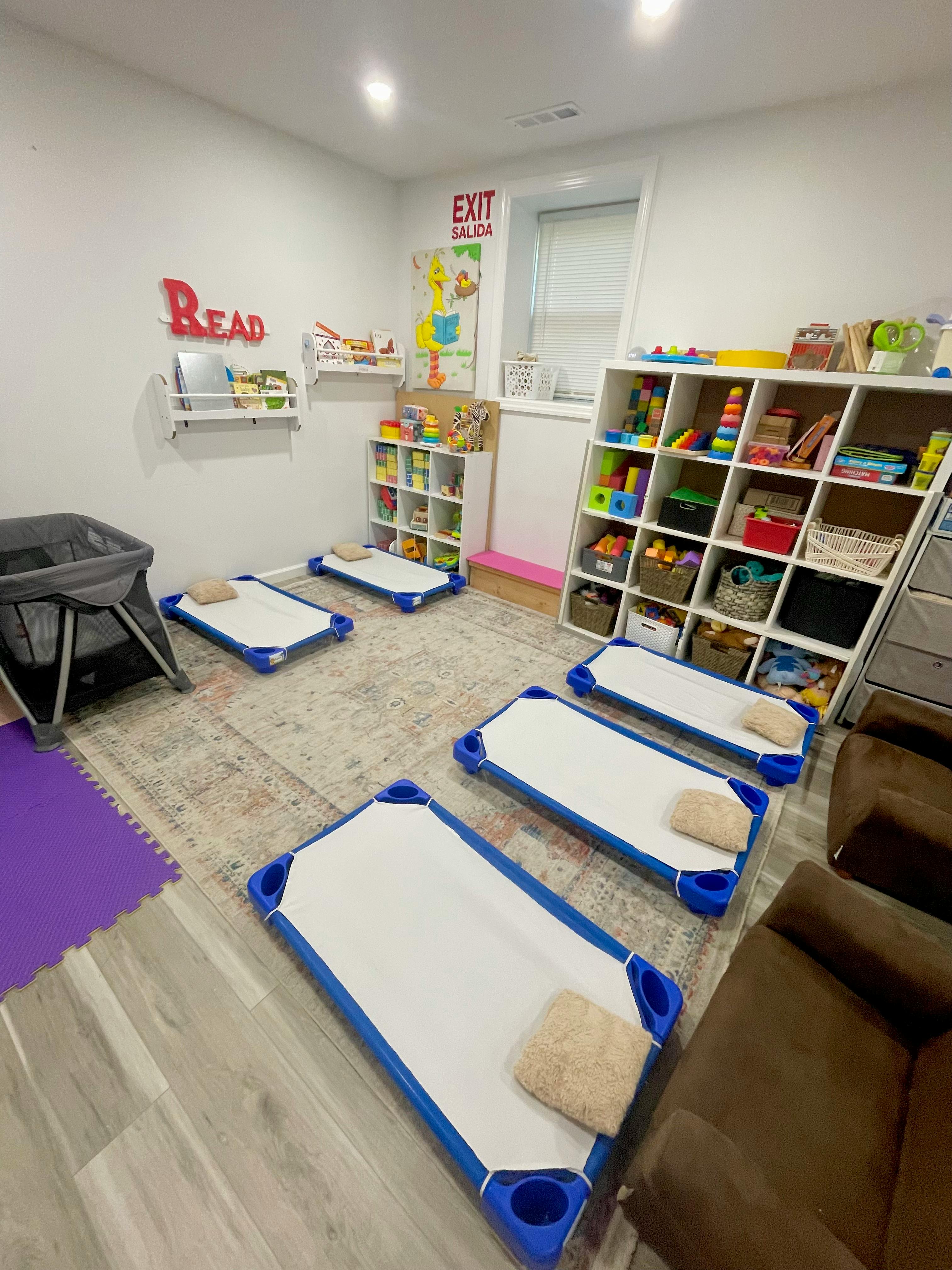 Childcare room with small cots and shelves filled with toys