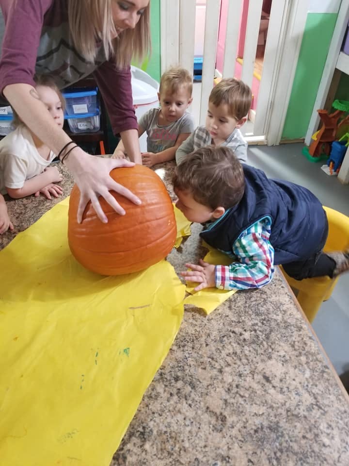 Person and children examining a pumpkin on a table