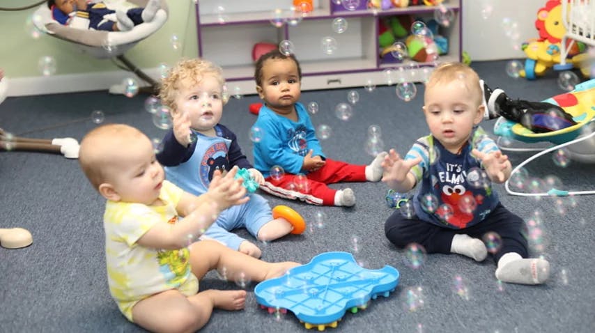Four children sitting on the floor playing with bubbles