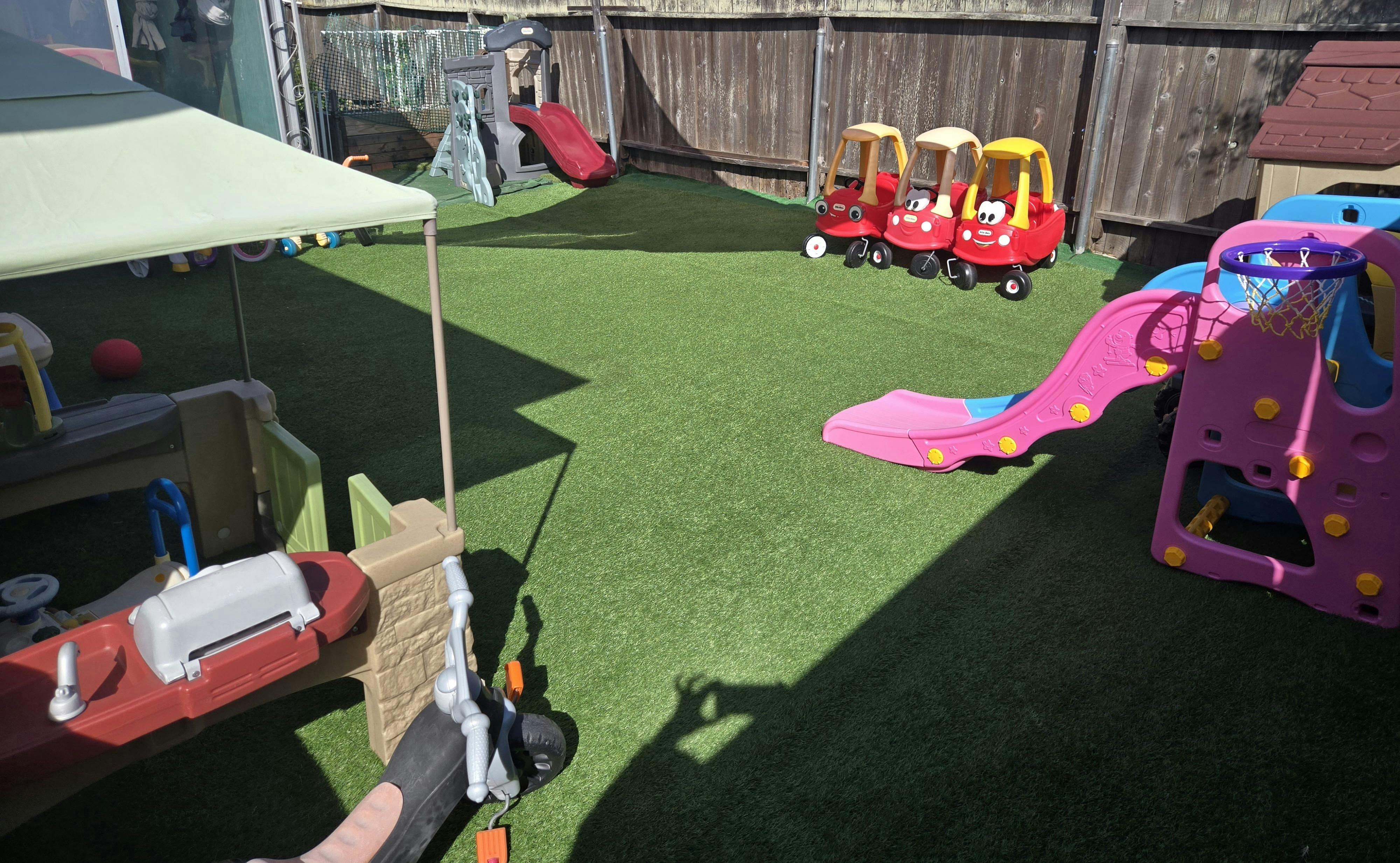 Playground with slides, toy cars, and an activity climber on artificial turf