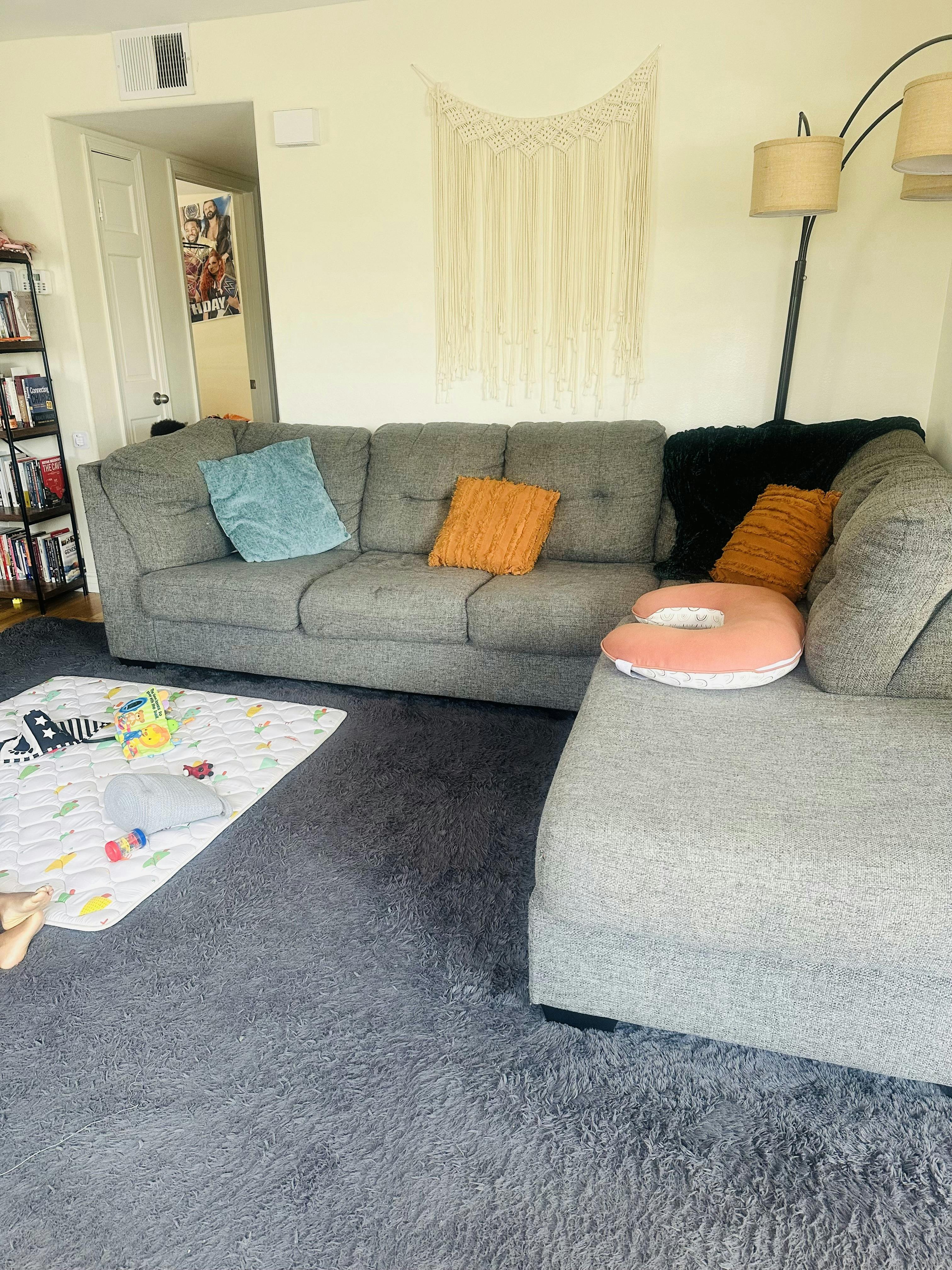 gray sectional sofa with throw pillows and a baby play mat on a shag rug