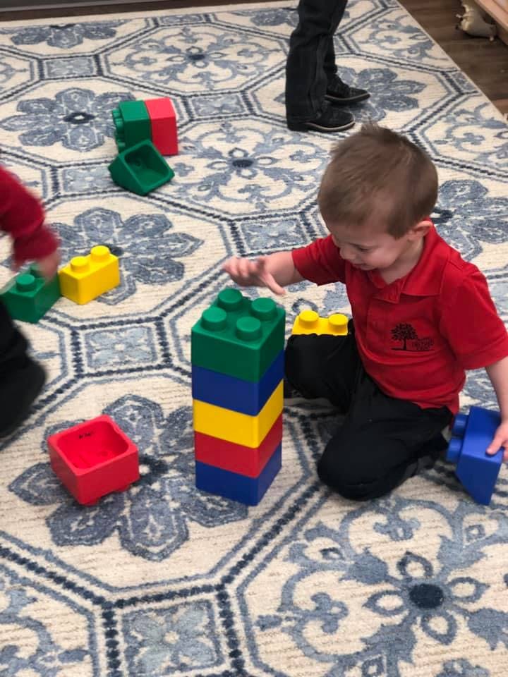 Child playing with large colorful building blocks on a patterned rug