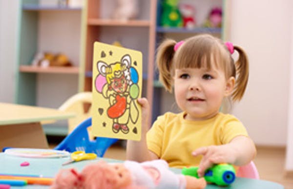 Child holding up a drawing of drawing of a cartoon character with balloons