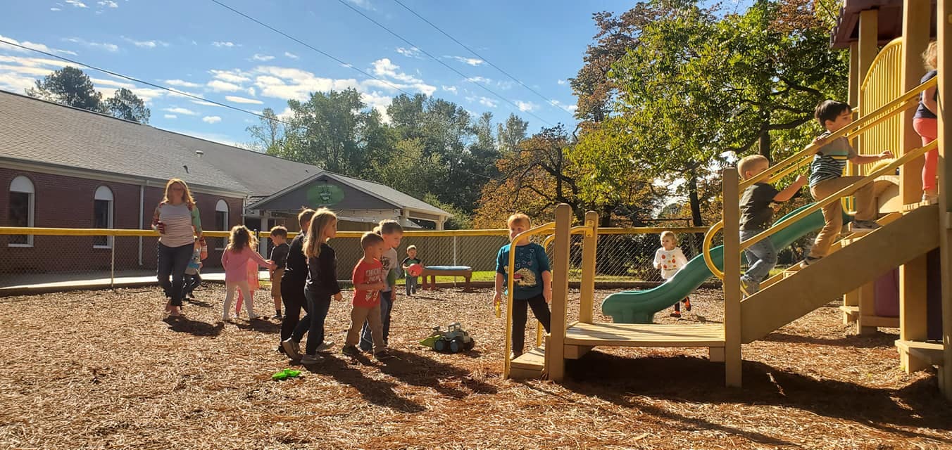 Children playing on a playground with a slide and climbing structure