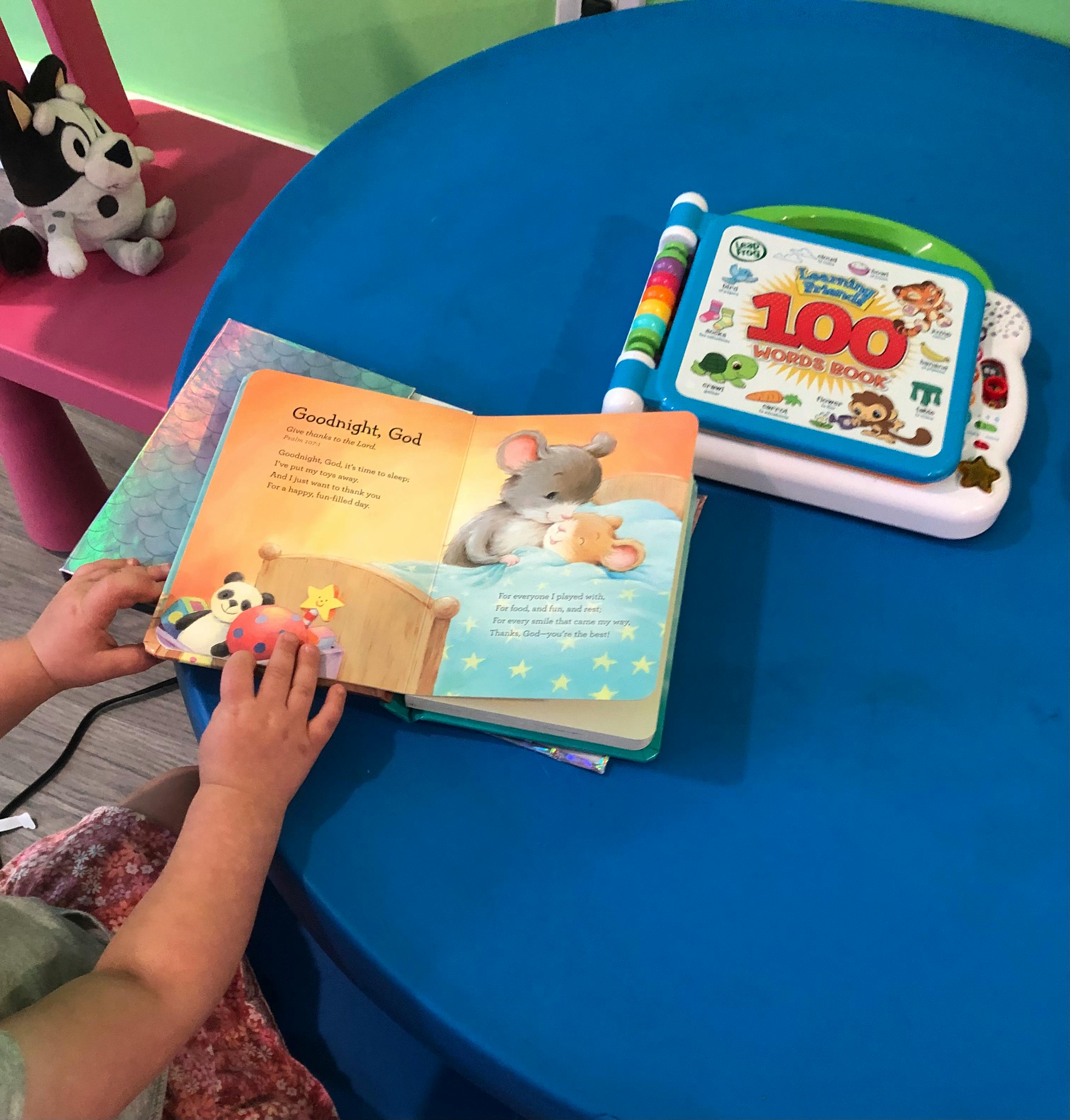 Child's hands holding an open storybook on a blue table