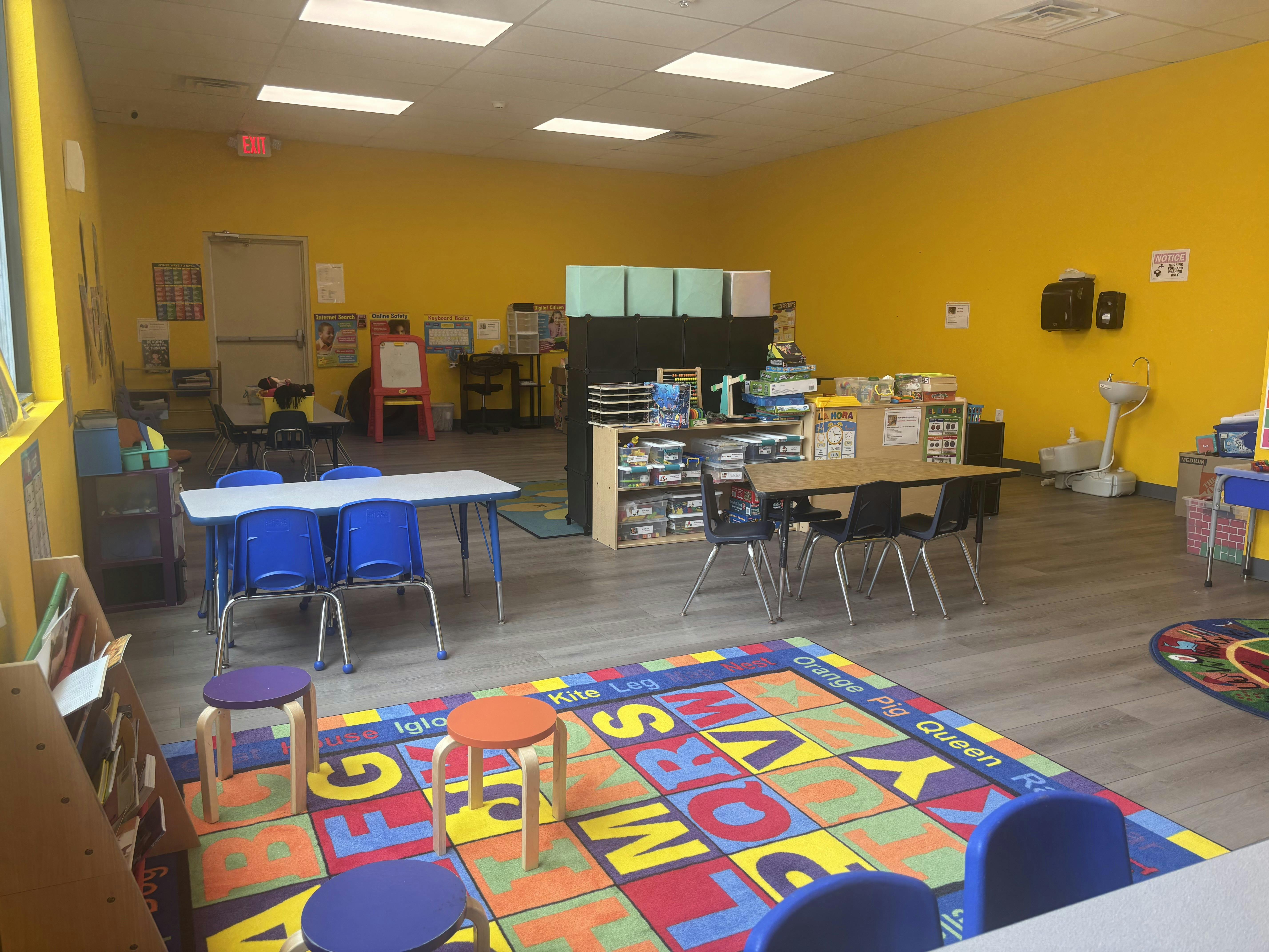 Classroom interior with small tables and chairs on an alphabet floor mat