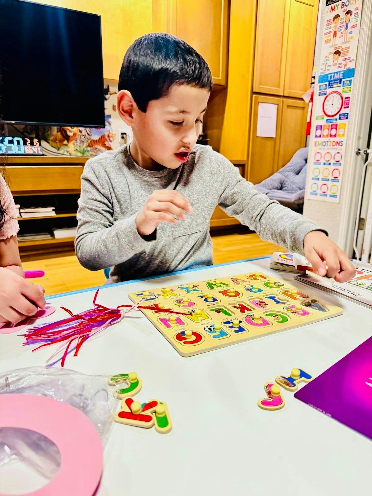 Child placing letters into an alphabet puzzle board at a table
