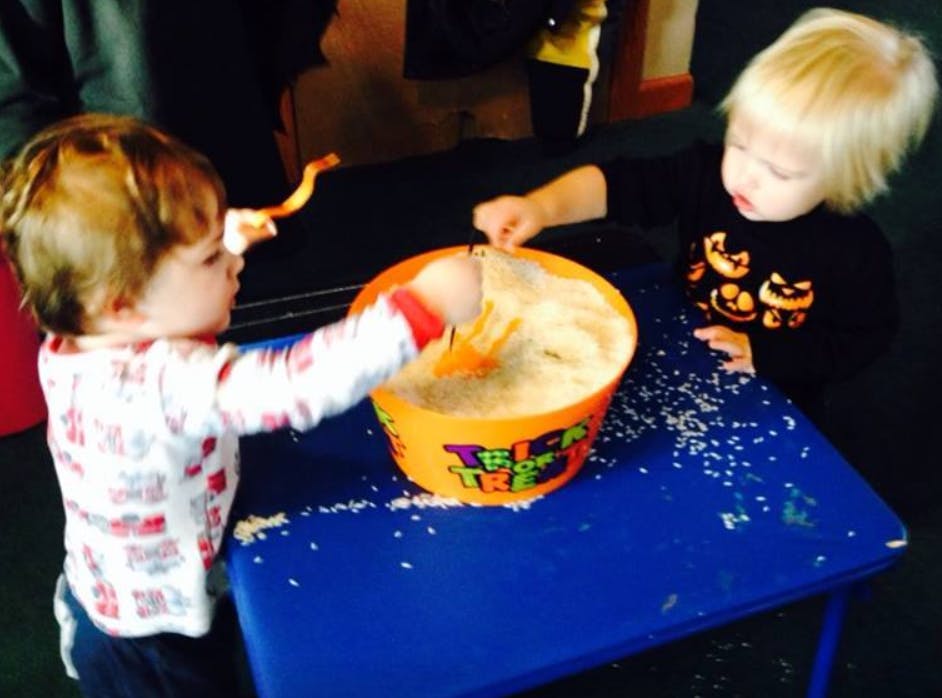 Two children playing with a sensory bin filled with rice