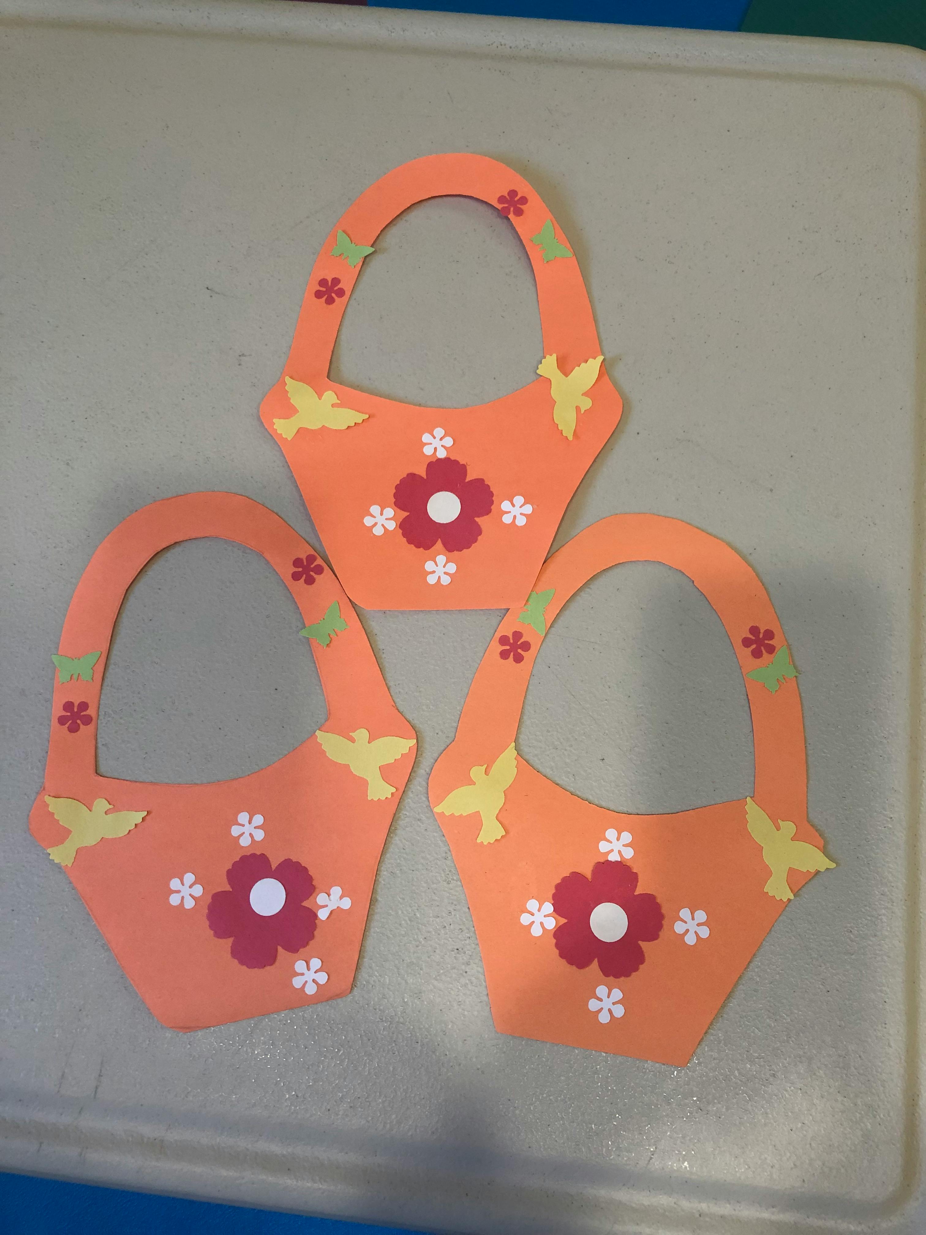 Three orange paper baskets with flower and bird cutouts