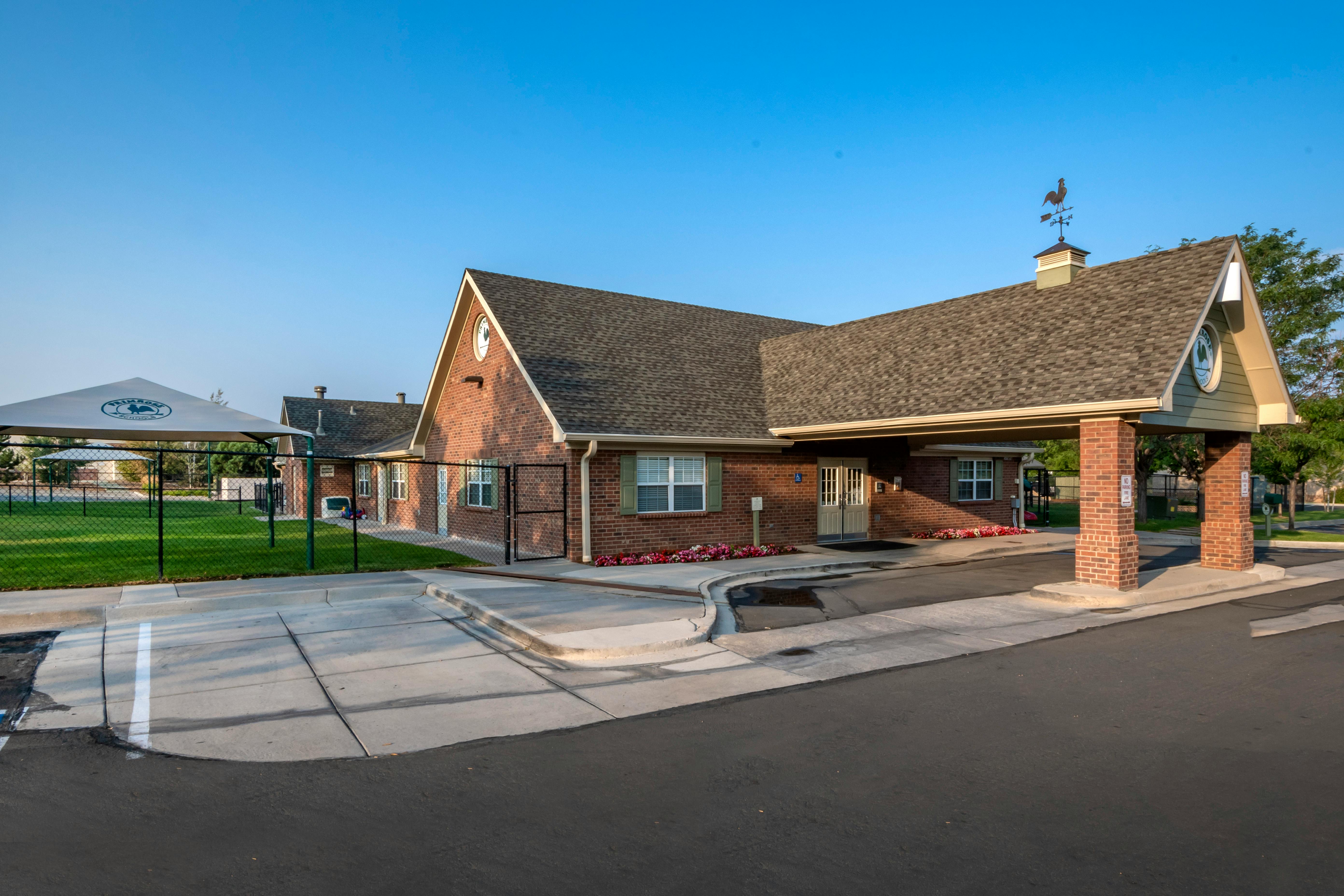 Brick building with a covered entrance and a fenced play area with a canopy