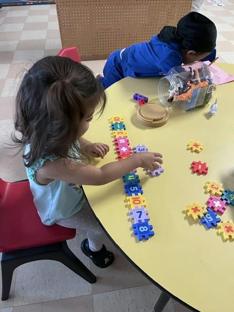 Child sitting at a table connecting numbered toy blocks