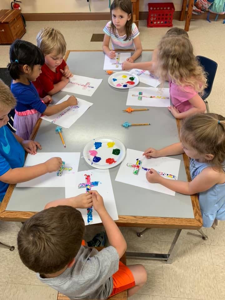Children painting crosses at a table