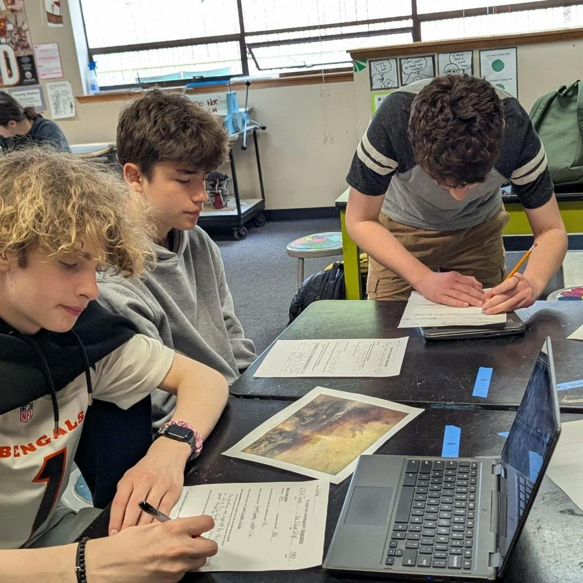 Three teens working at a table in a classroom