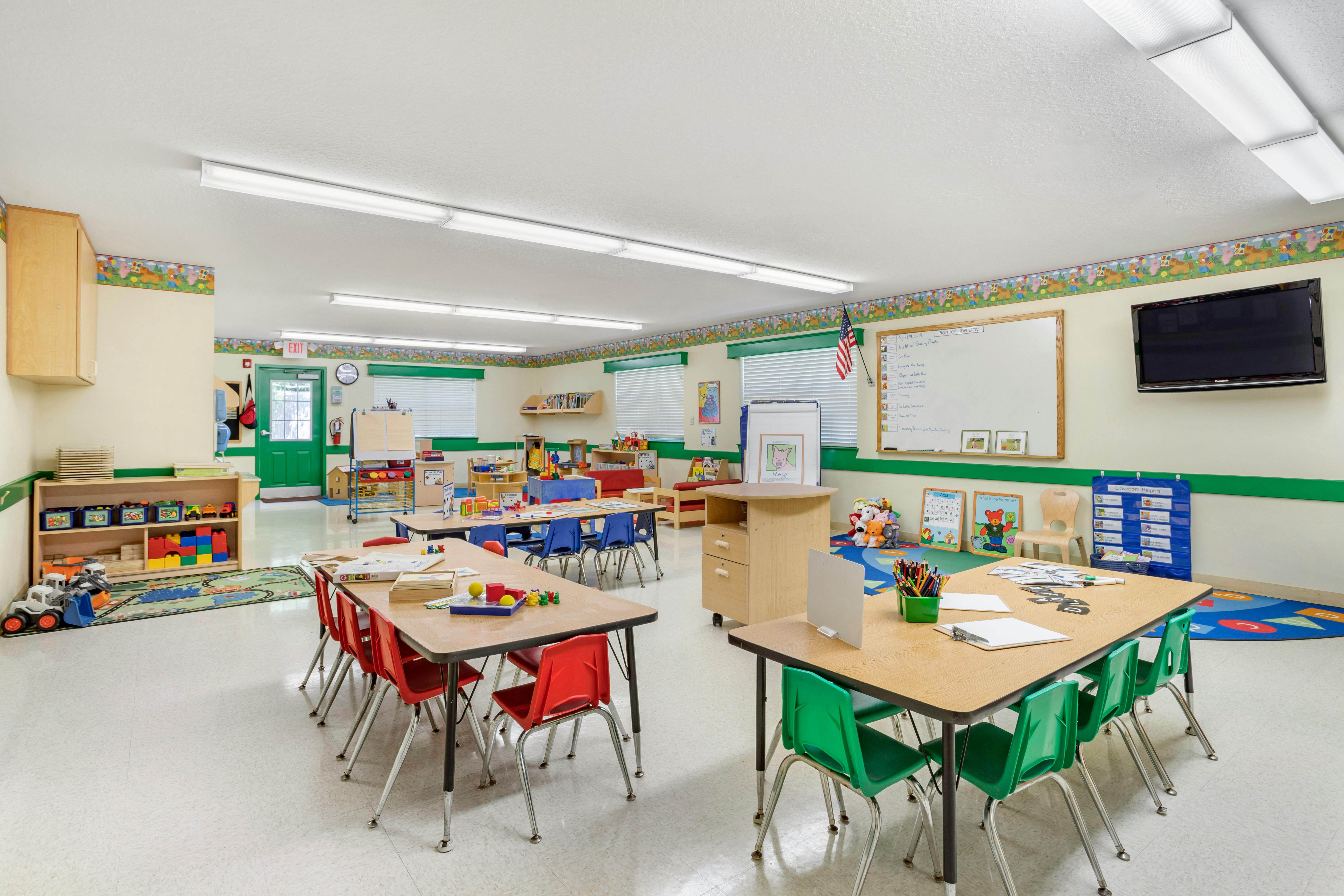 Classroom with tables, chairs, toys, and a whiteboard