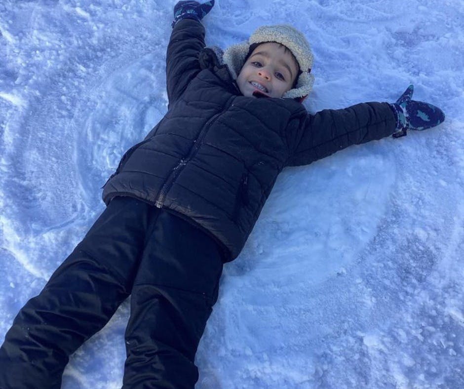 Child lying in snow making a snow angel