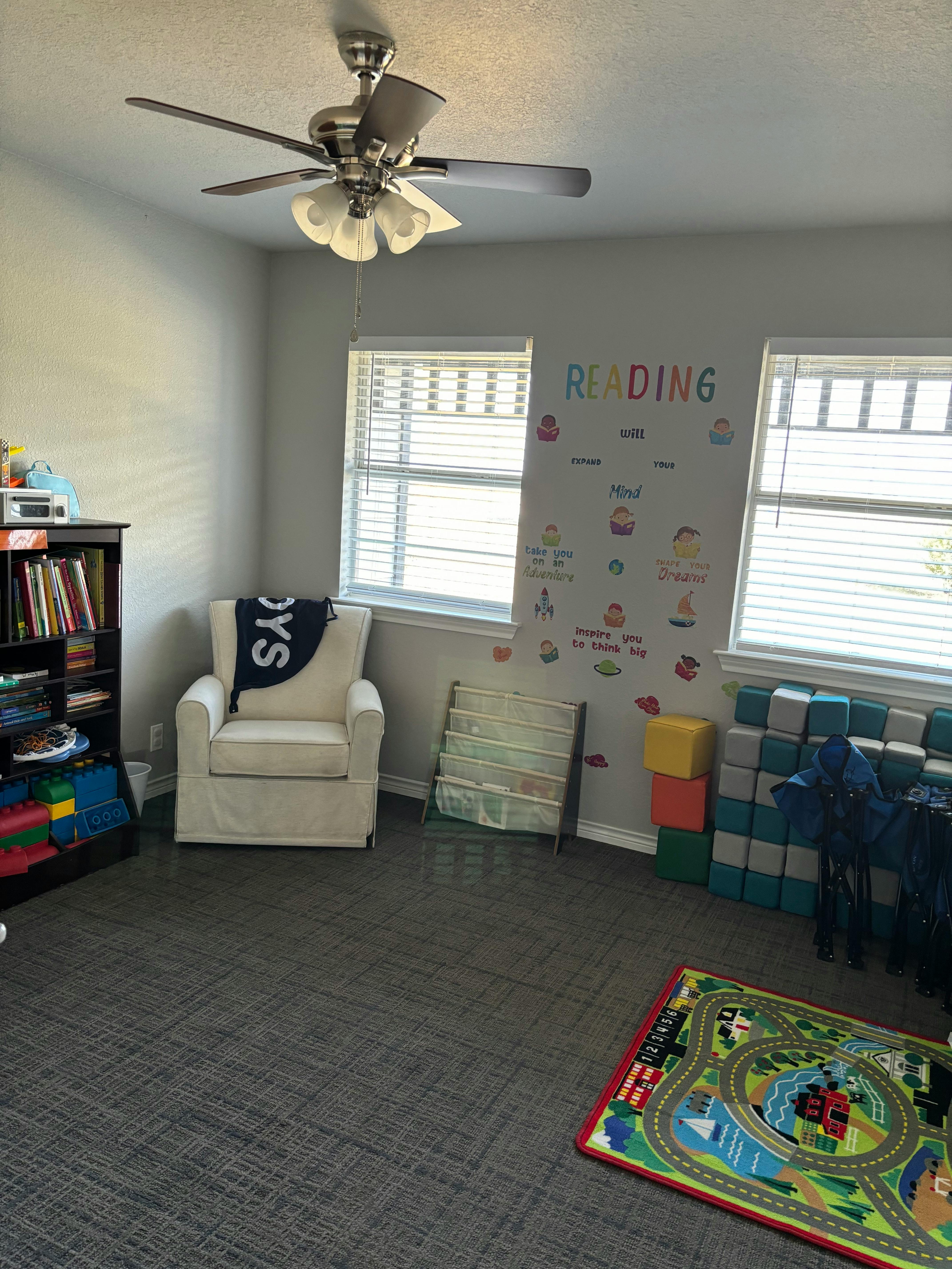 Reading room with a chair, bookshelf, and play rug