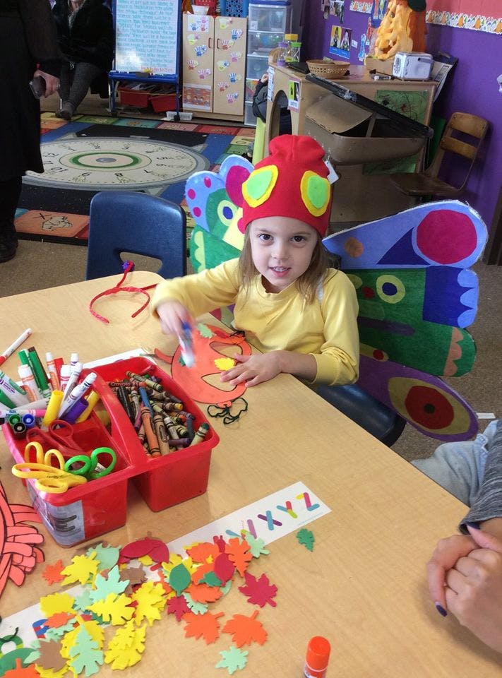Child in a classroom making crafts at a table with craft supplies