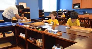 Adult and children working at tables in a classroom