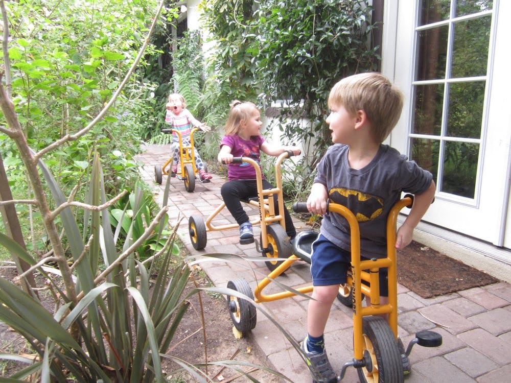 Children riding tricycles outdoors