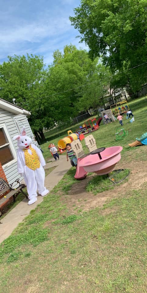 Person in a white bunny costume with children on a playground