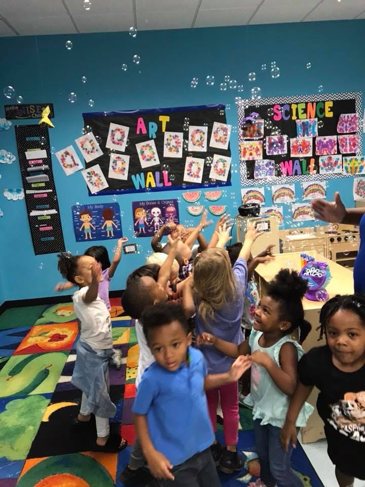 Children reaching for bubbles in a classroom
