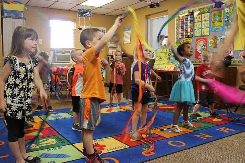 Children waving colorful ribbons in a classroom