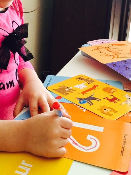Child tracing the number 2 on an orange card