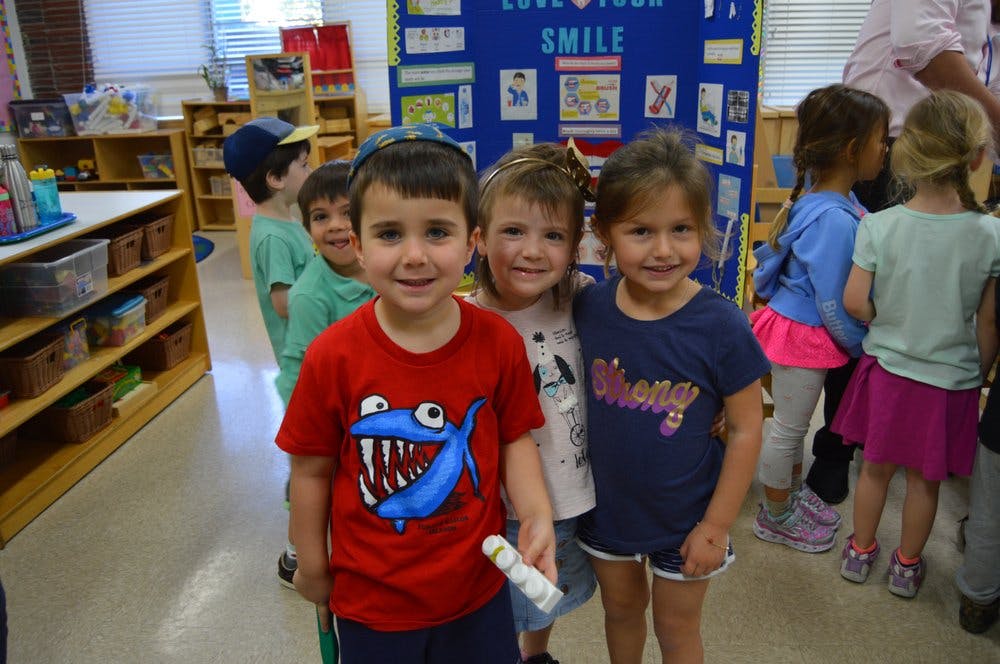 Three children standing together in a classroom