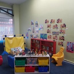 Playroom with toy shelf, yellow chair, and pictures on the wall