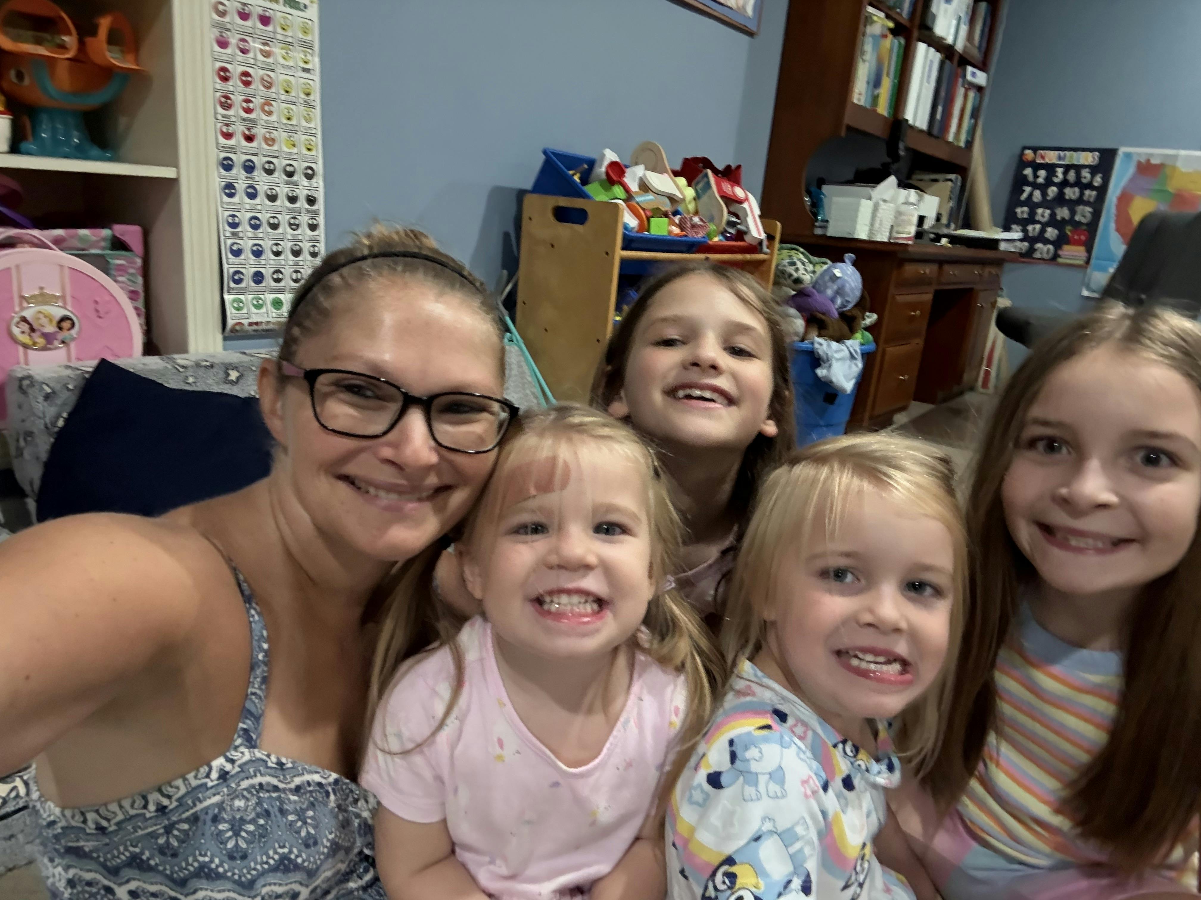 A person and four children smiling together in a room